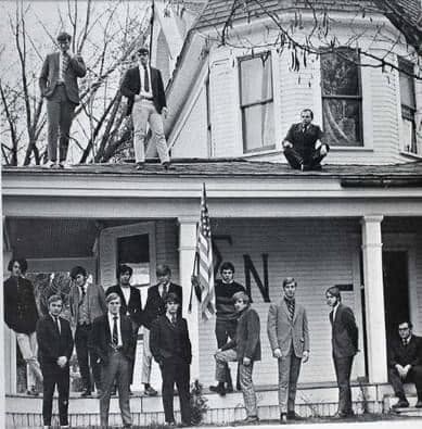 Members of Beta Delta Theta standing in front of and on the roof of the original chapter house in the 1960s at Eastern Washington State College